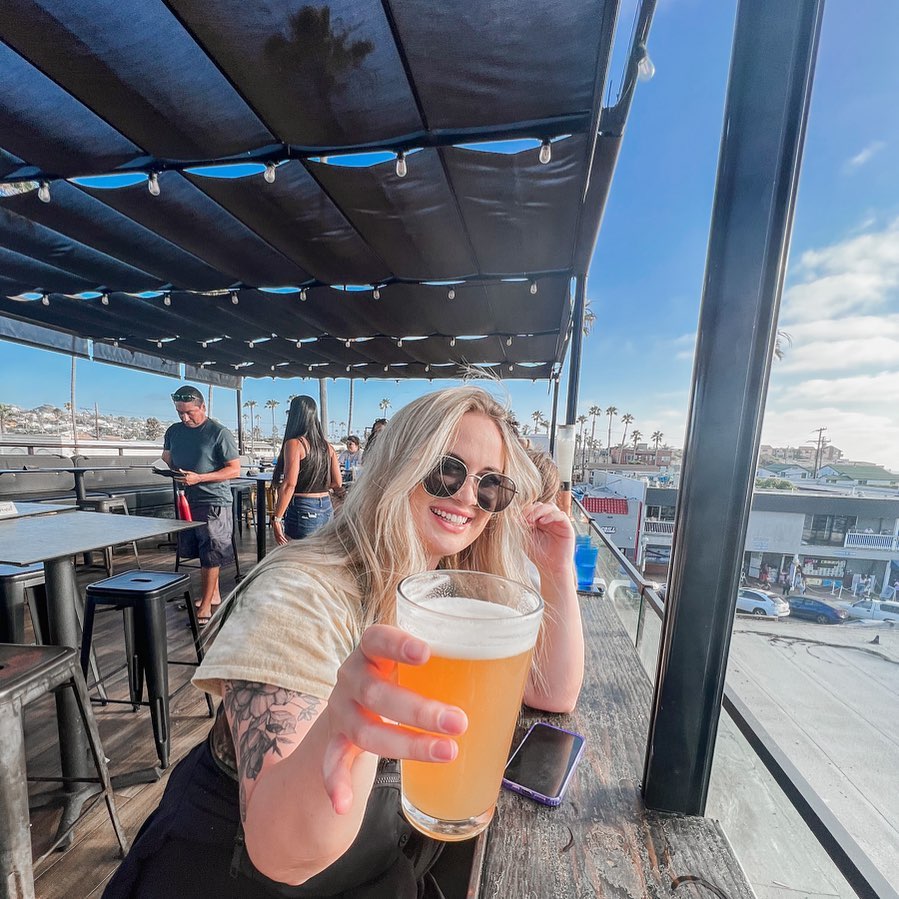 A girl enjoying a drink at Ocean Beach in San Diego