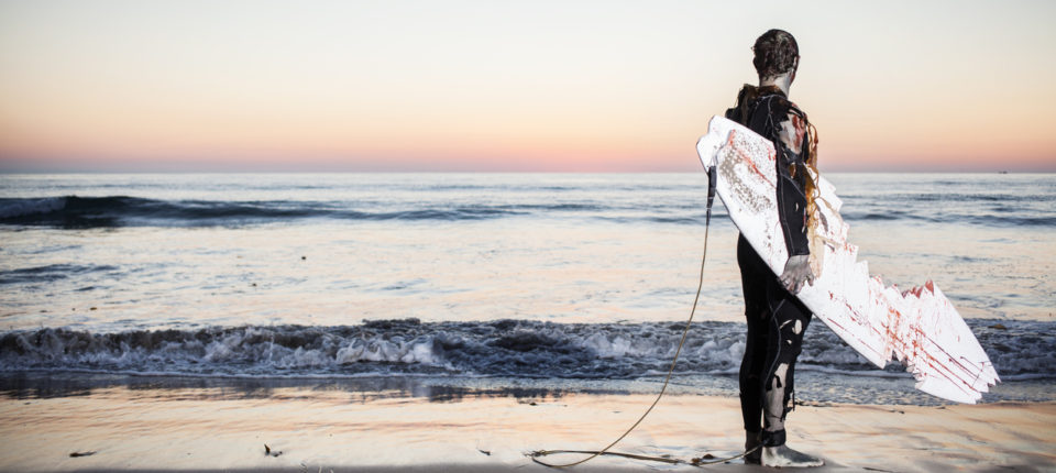A man standing with a surfboard near the beach