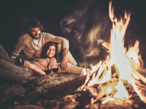 Happy relaxed couple enjoying in their date night by the campfire.