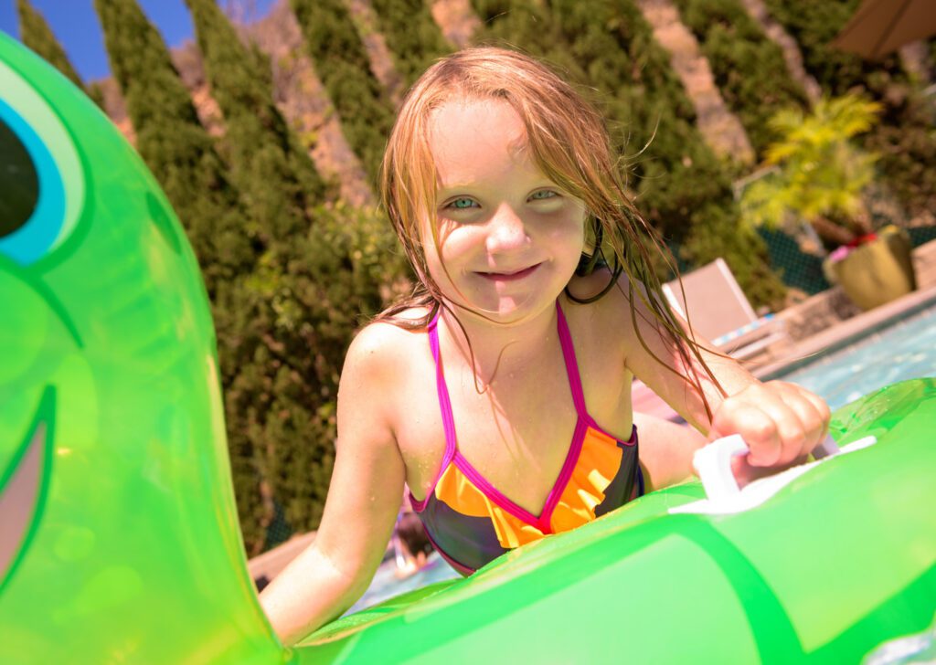 Little girl playing on a floaty in the pool