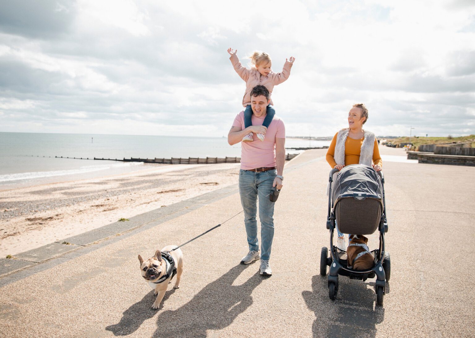 Family with dog and stroller walking down the beach