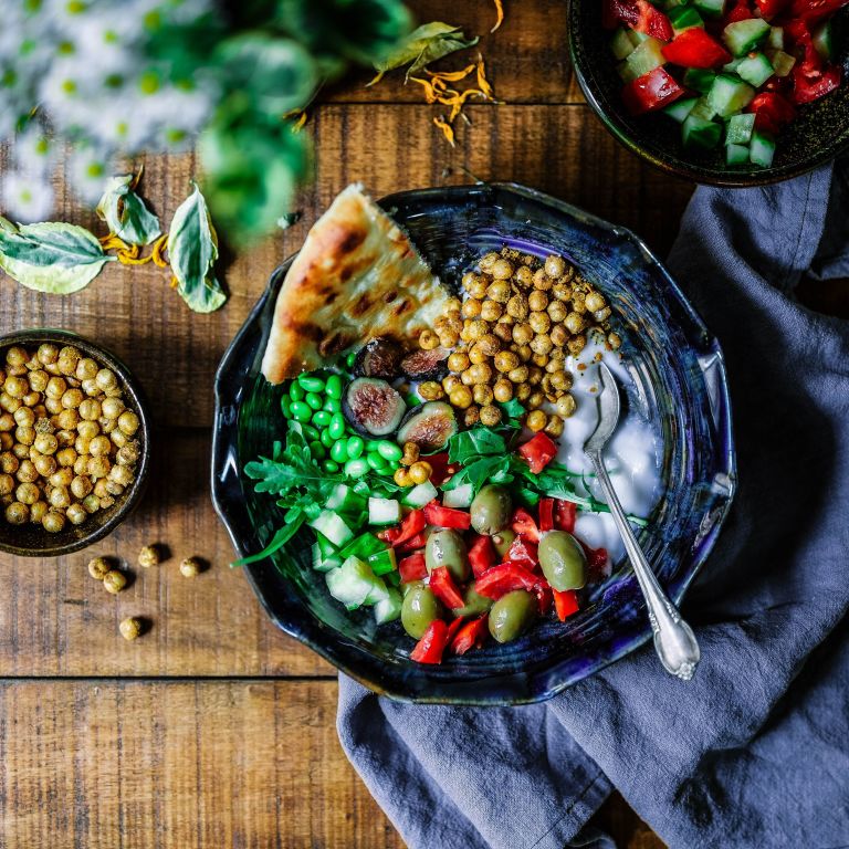 a bowl full of colorful vegetables and flat bread