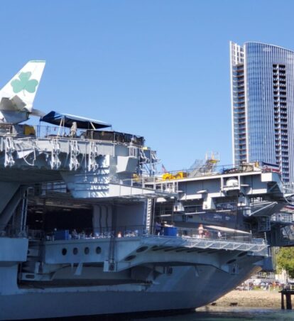 The USS Midway aircraft carrier docked with modern San Diego skyscrapers in the background.
