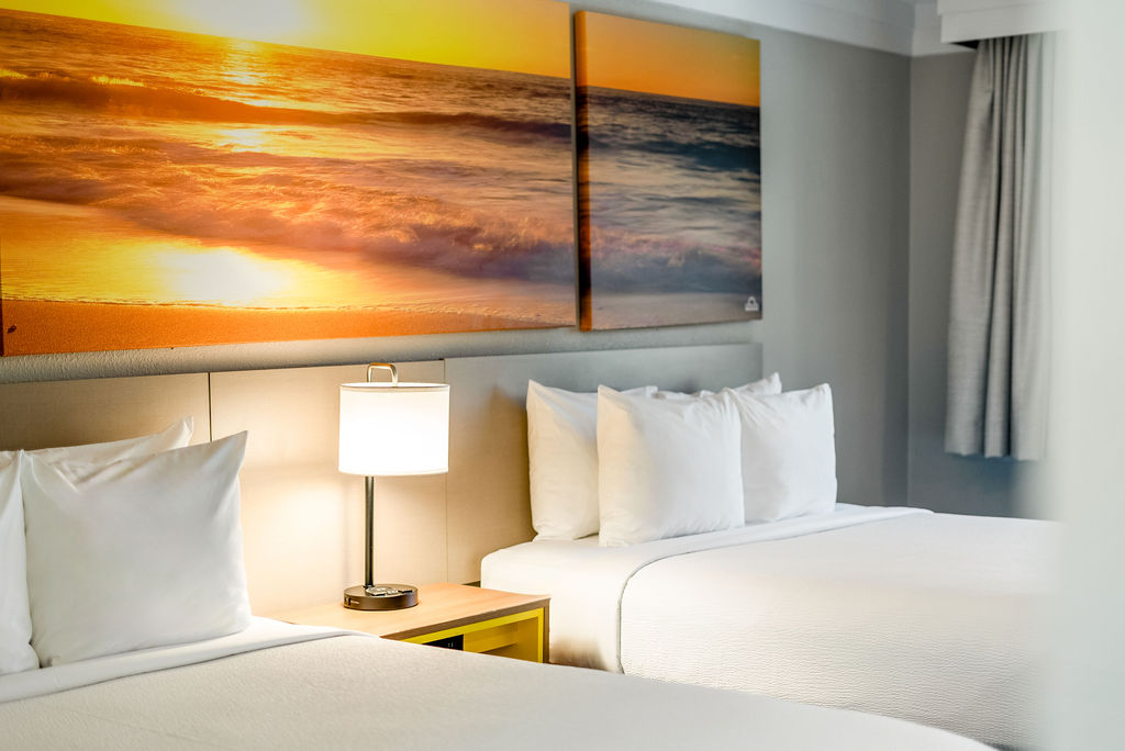Hotel room with two beds and sunset artwork.