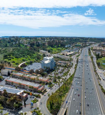 Aerial view of highway, hotels, and green hills.