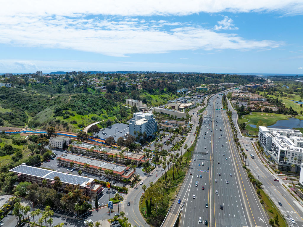 Aerial view of highway, hotels, and green hills.