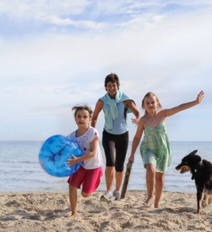 Family with children and dog playing on beach.