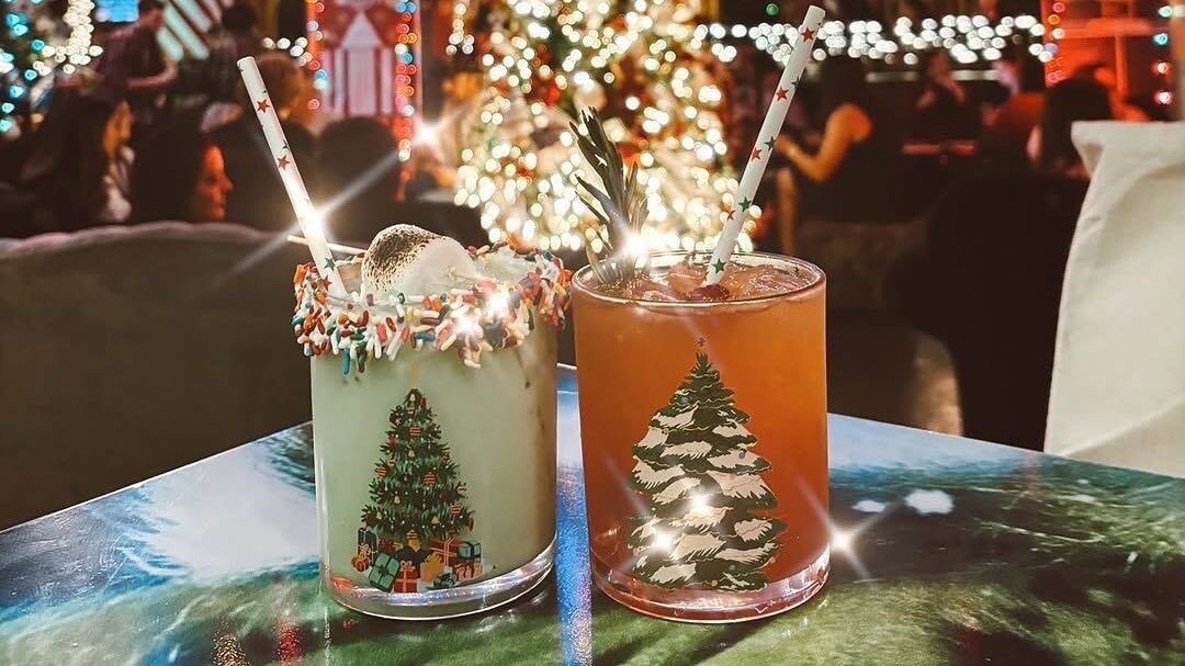 Two holiday cups on table in front of tree