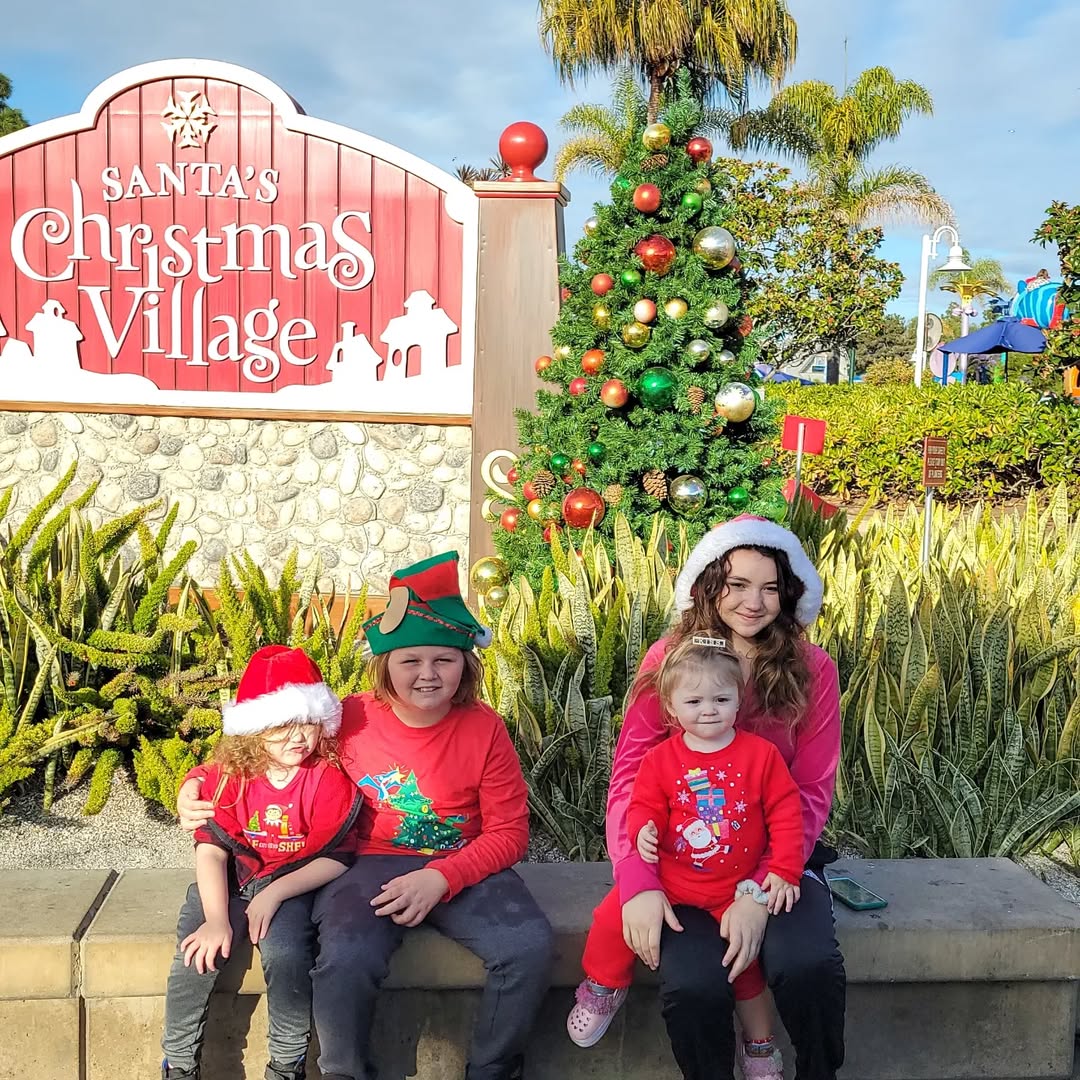 Family sitting in front of Santa's Christmas Village Sign at SeaWorld California