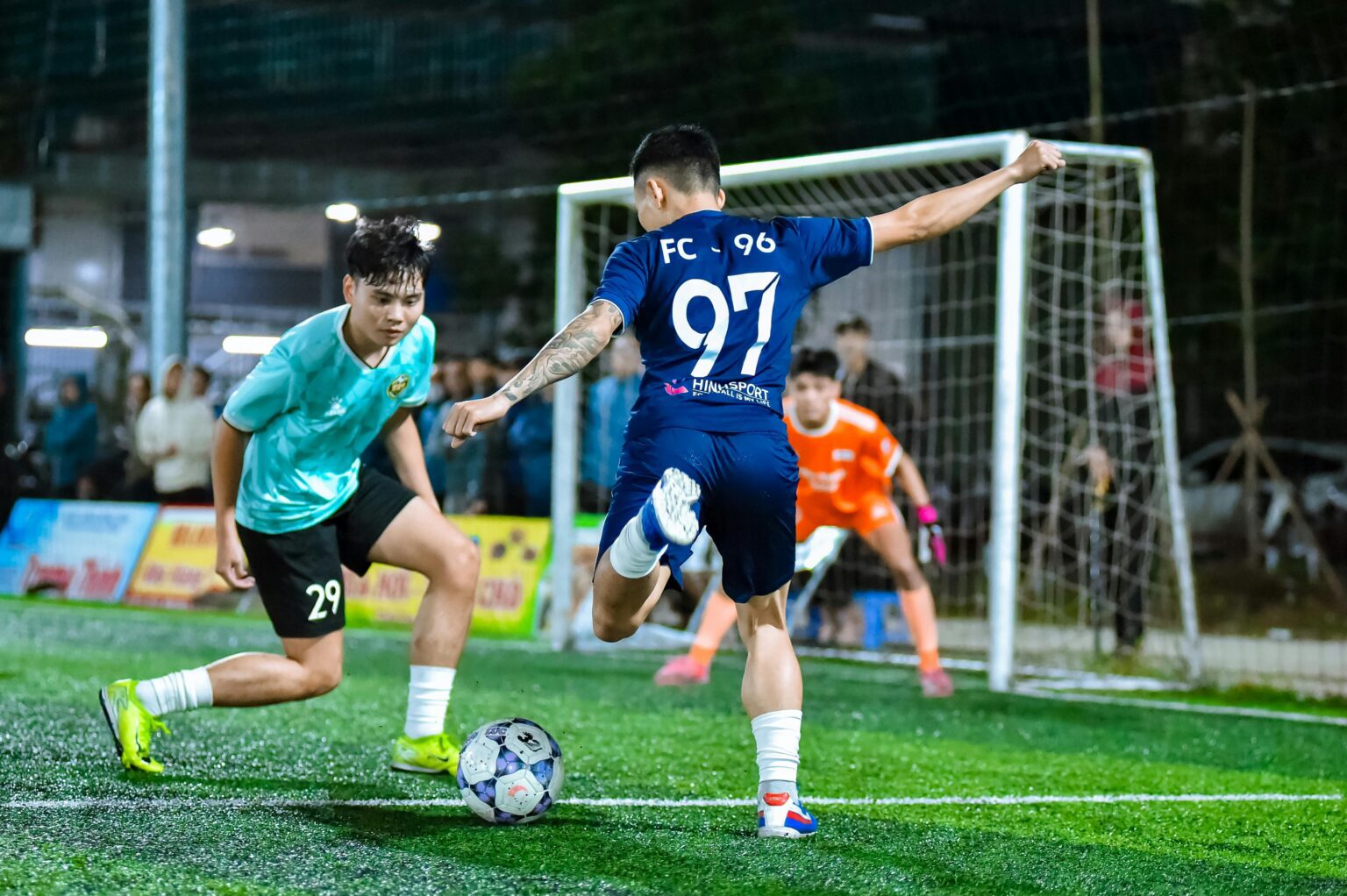 Someone kicking soccer ball into net