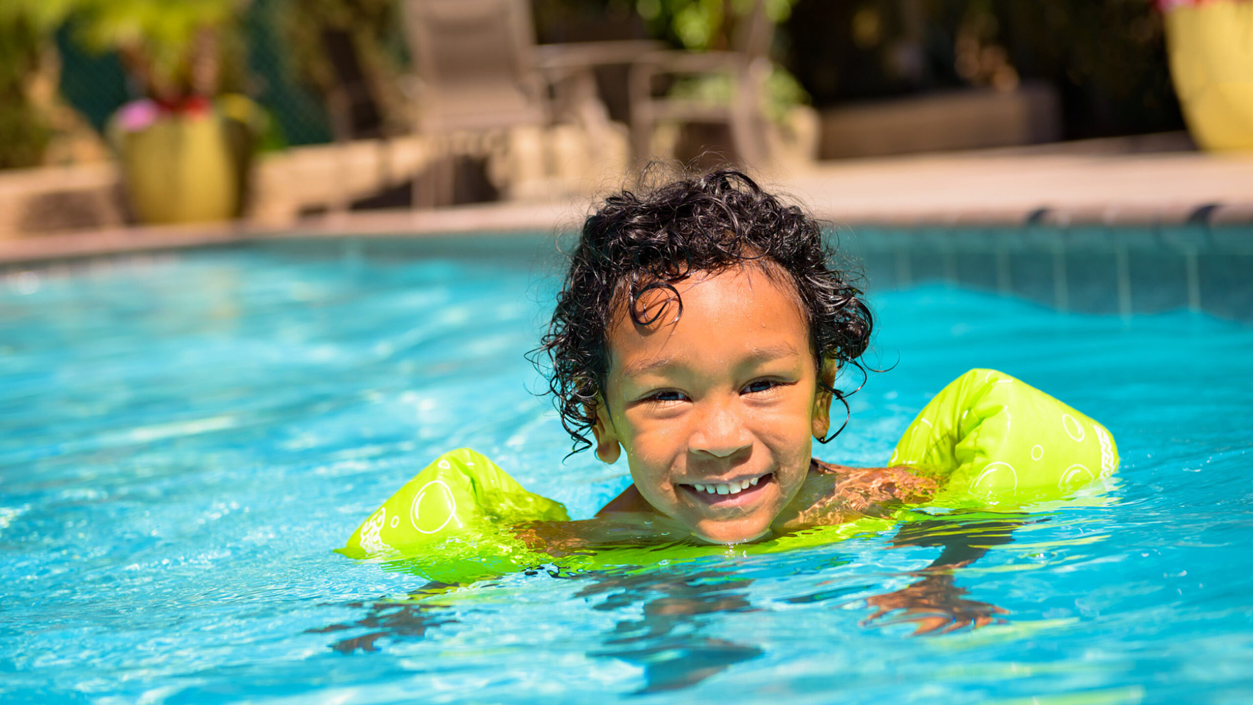 a child in the pool wearing arm floaties
